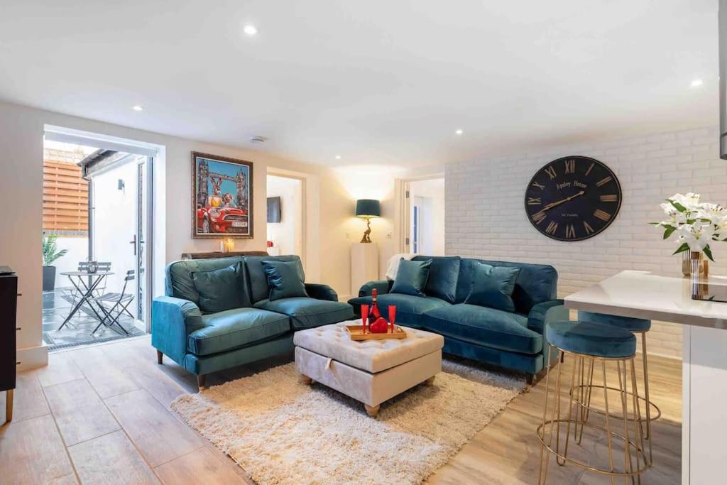 a living room with two blue couches and a clock at Wanstead, Escape London in London-Luxury 2 Bed in London