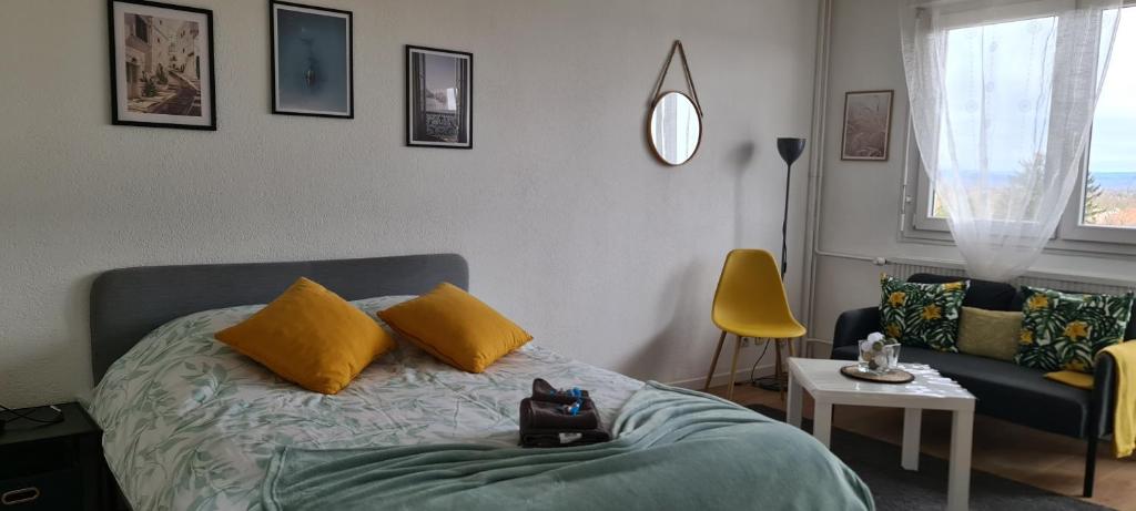 1 dormitorio con cama con almohadas amarillas y sofá en Studio KULLA avec terrasse 5mn Basel Airport, en Saint-Louis