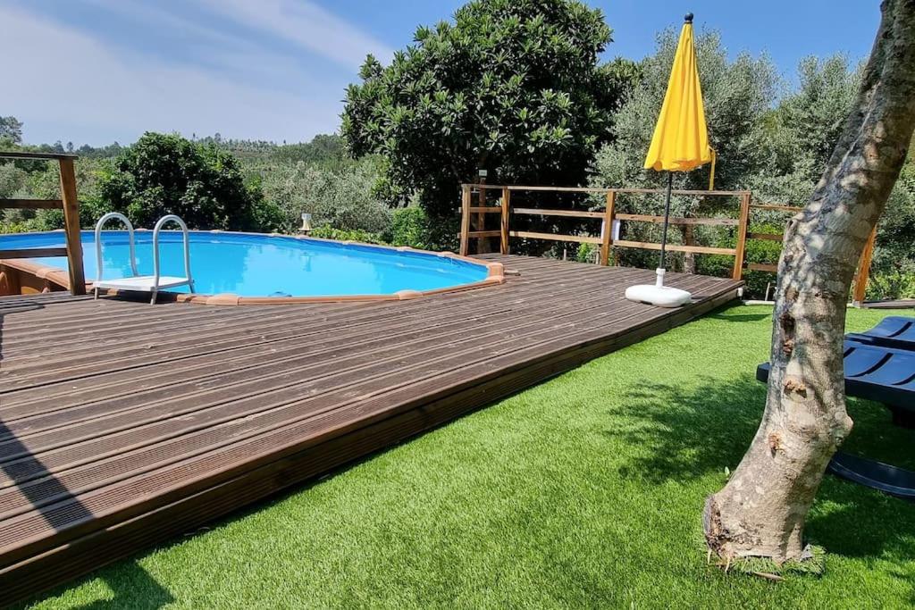una terraza de madera con piscina y sombrilla amarilla en Casa do Riu, 