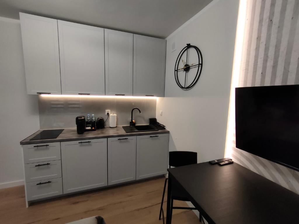 a kitchen with white cabinets and a black table at Slate Apartament Polanica - Zdrój in Polanica-Zdrój