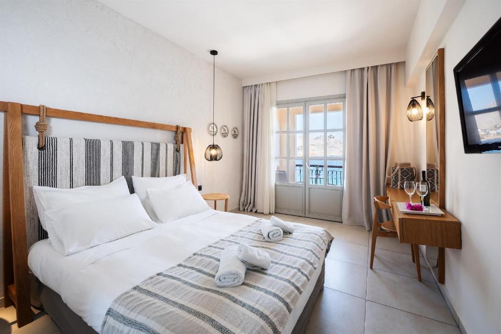 a bedroom with a large bed with towels on it at Pedi Beach Hotel in Symi