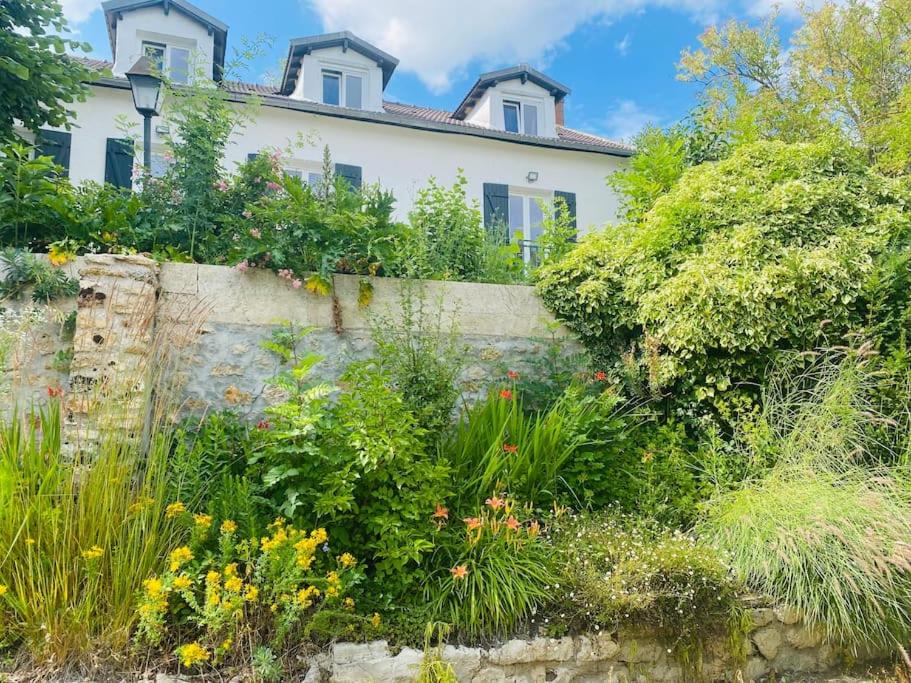 uma casa com um jardim em frente a uma parede em Magnifique maison au cœur d'un jardin paysager em Breuillet