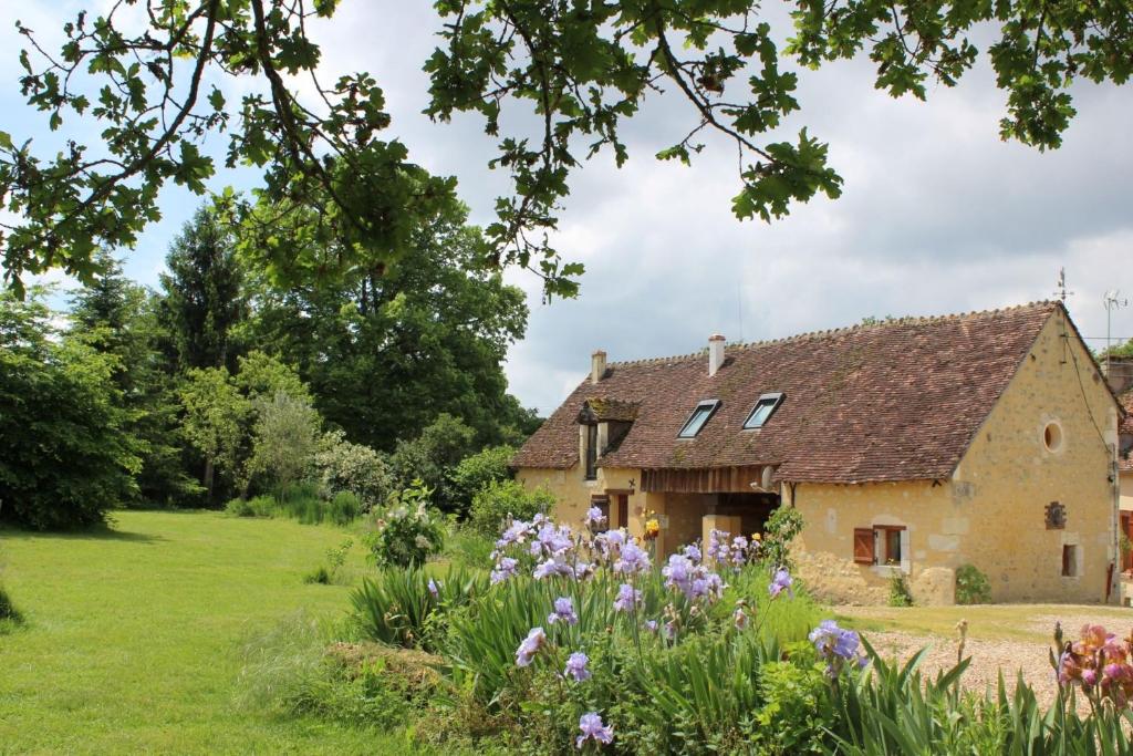 een oud stenen huis in een veld met bloemen bij Gîtes à l'ombre des chênes in Châteauvieux