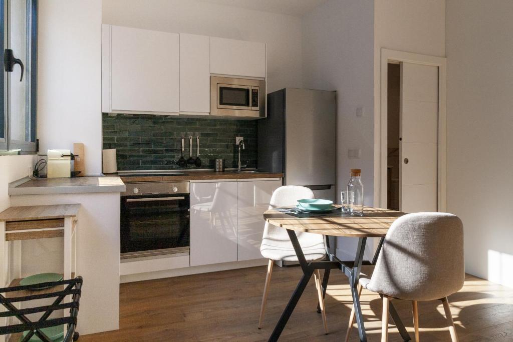 una cocina con armarios blancos y una mesa con sillas. en Simancas by SharingCo, en Madrid