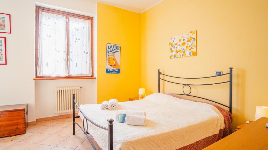 een slaapkamer met een bed met gele muren en een raam bij Al Bivio Peschiera - Italian Homing in Peschiera del Garda