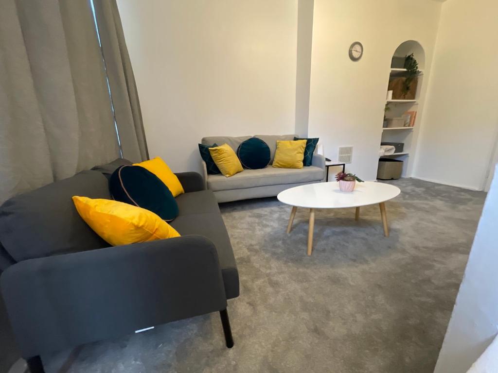 a living room with a couch and a table at Tooting Lodge London - Cosy 2 bedroom house with garden in London
