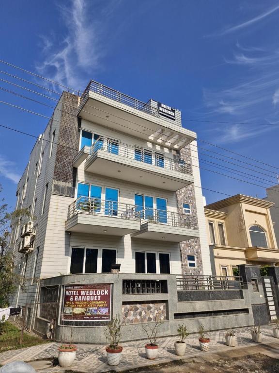 a tall white building with blue windows and balconies at Hotel Wedlock 39 in Gurgaon