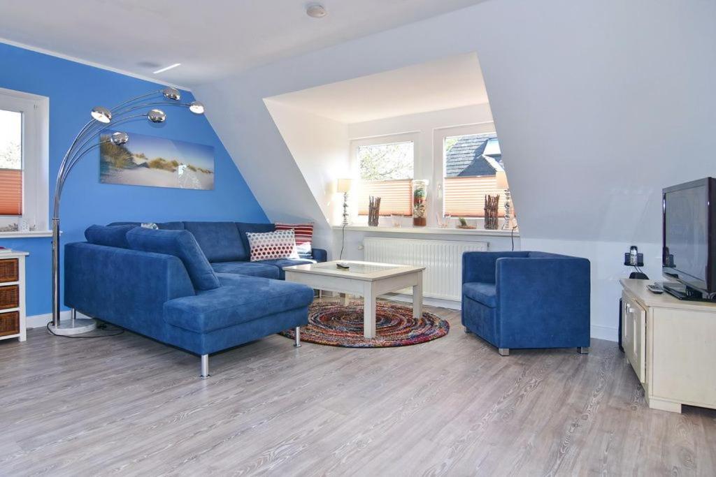 sala de estar con sofá azul y TV en Amselweg 5, en Süderende