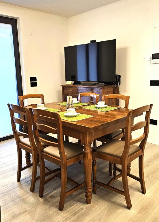 a wooden dining room table with chairs and a flat screen tv at ANDALO RELAX APARTMENT in Andalo