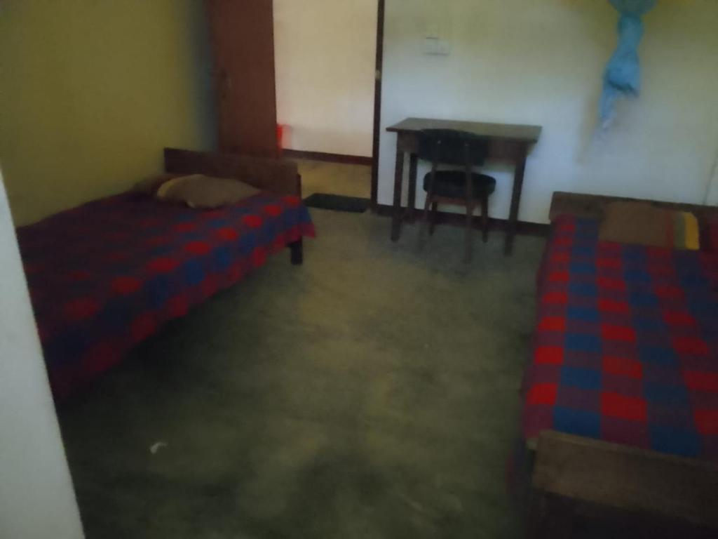 Cette chambre comprend un lit, un bureau et une table. dans l'établissement PCU, à Trincomalee