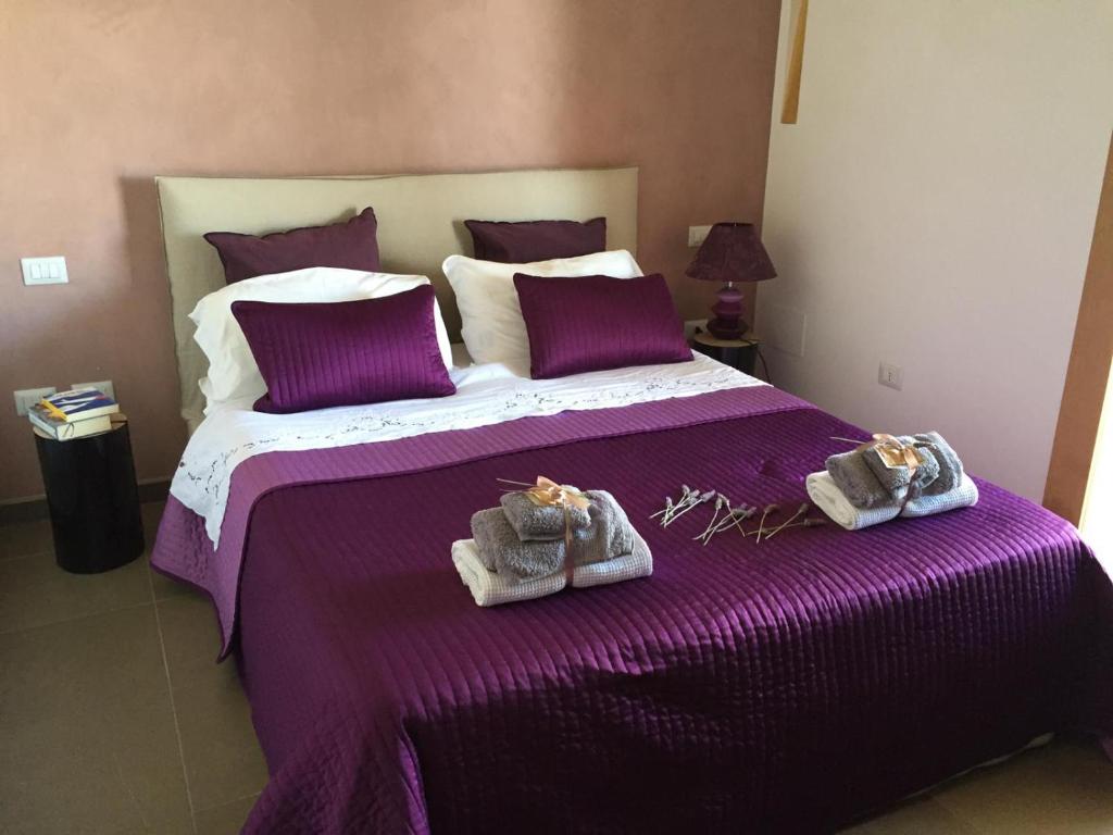 a bedroom with a purple bed with towels on it at Castellabate House in Santa Maria di Castellabate