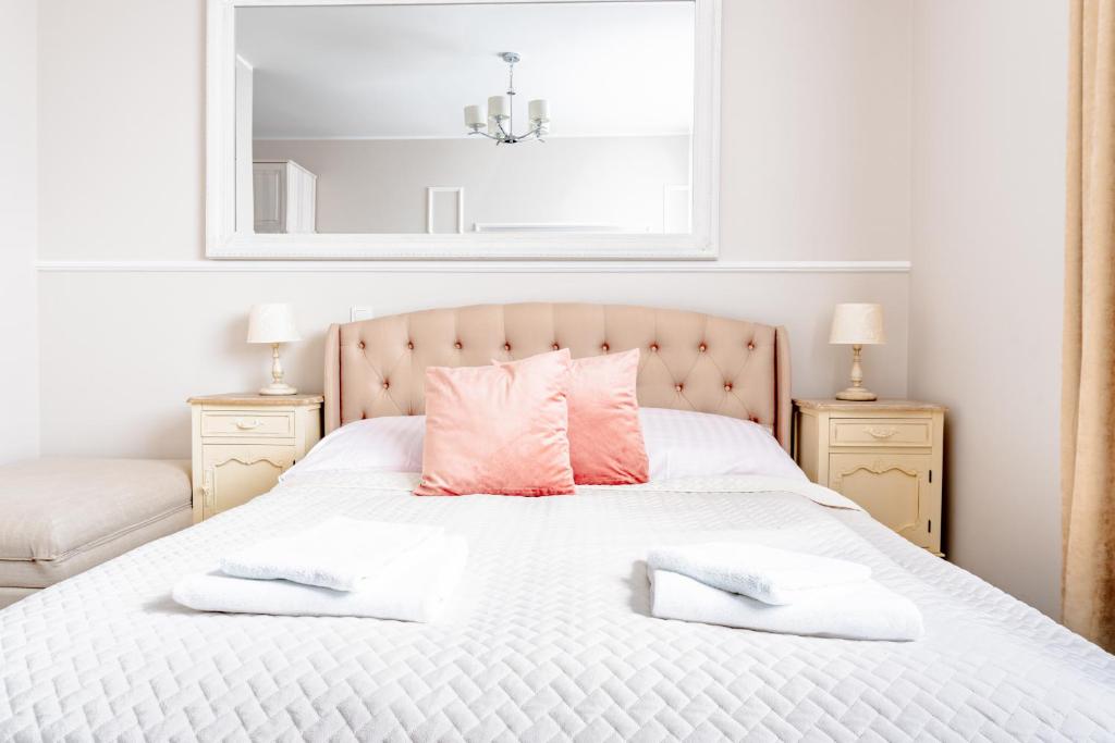 sypialnia z białym łóżkiem i różowymi poduszkami w obiekcie Filip Pokoje - Osłonino nad zatoką w mieście Osłonino