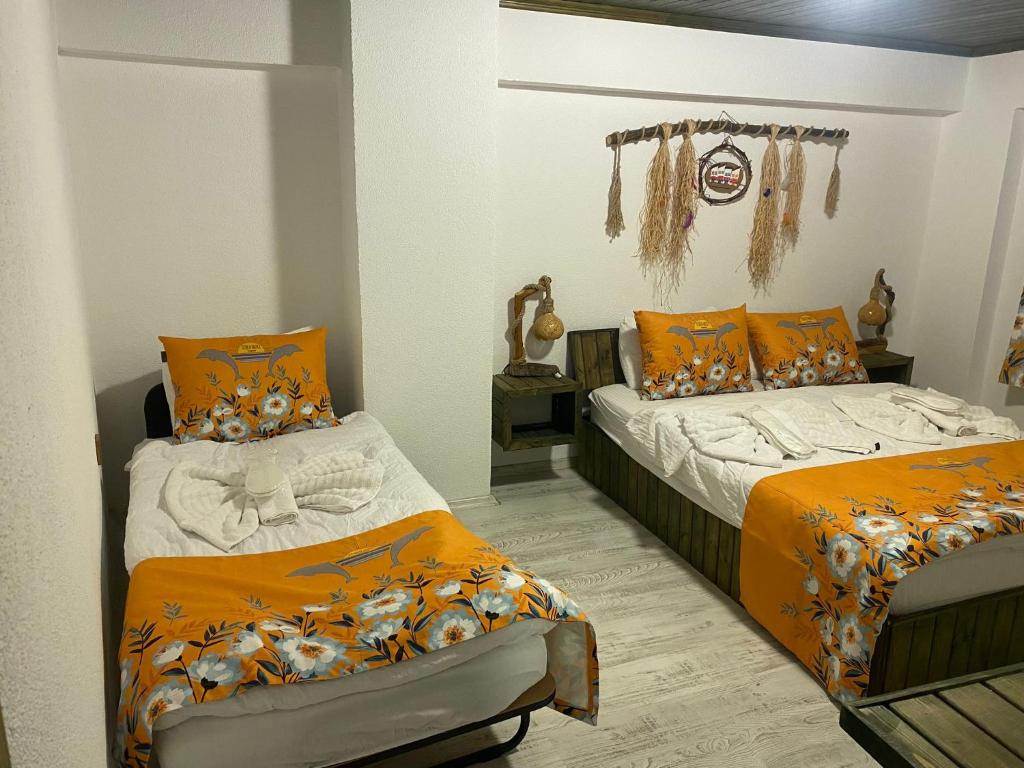 2 camas en una habitación con edredones de color naranja en Scala Otel, en Cesme
