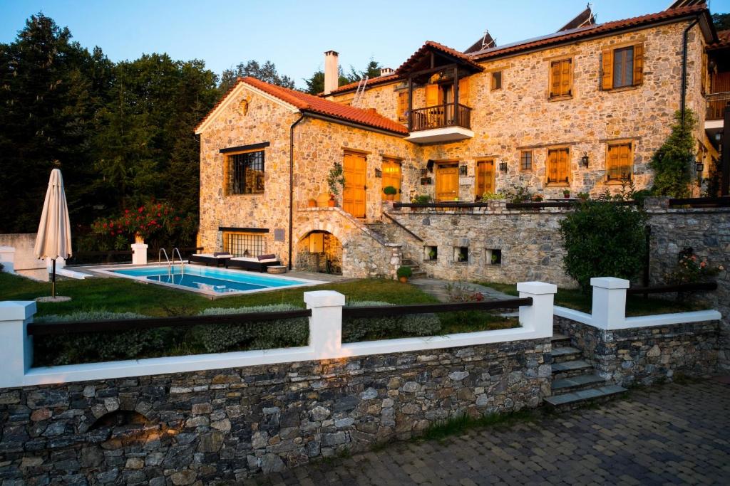 a stone house with a swimming pool in front of it at Eos - Authentic Experience in Skíti