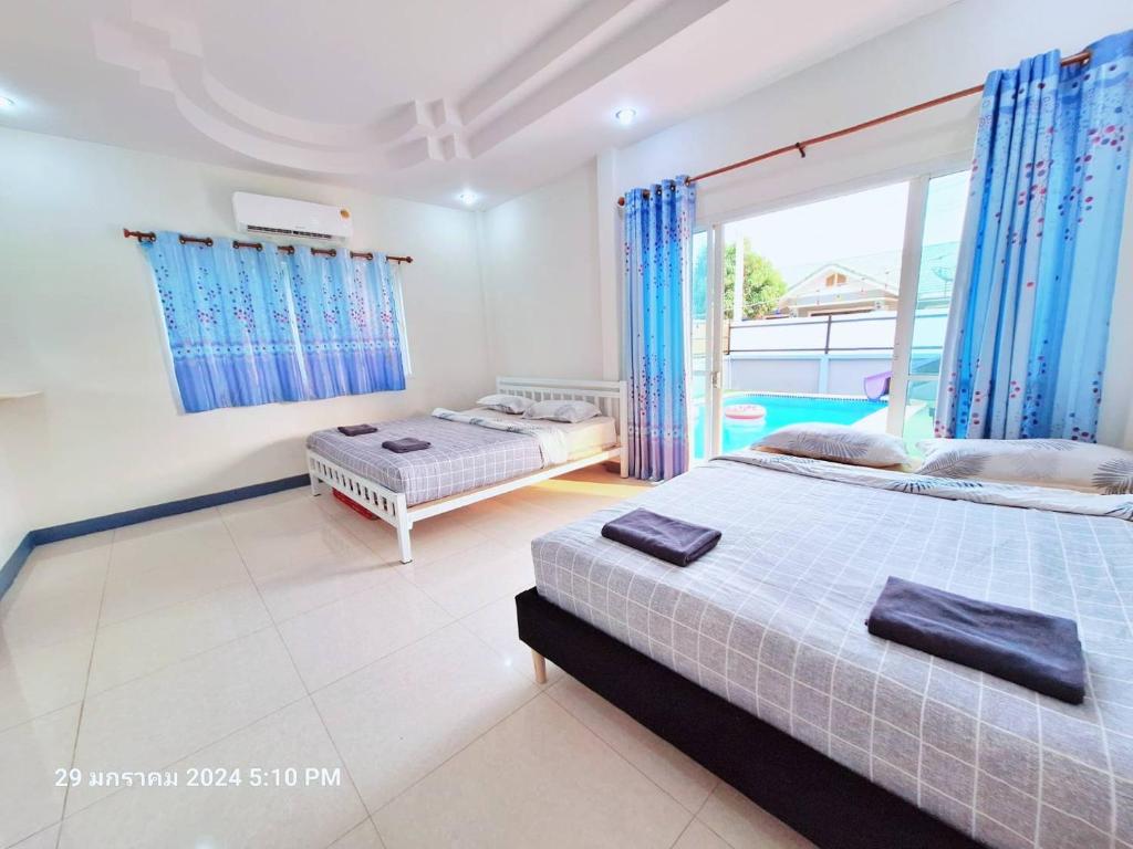 two beds in a bedroom with blue curtains at มัลดีฟส์ เวนิซ ไมอามี่ กรีนที หัวหินพูลวิลล่า Maldive Venice Miami Green Tea Hua-Hin Pool Villa in Hua Hin