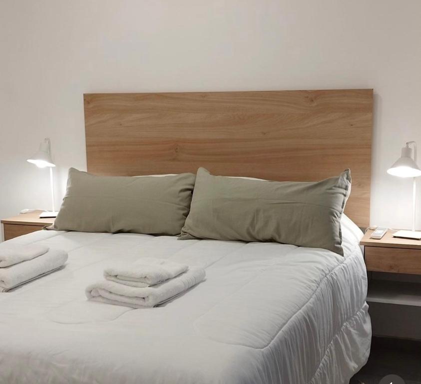 a white bed with two towels on top of it at Apart Hotel Concepcion in Concepción