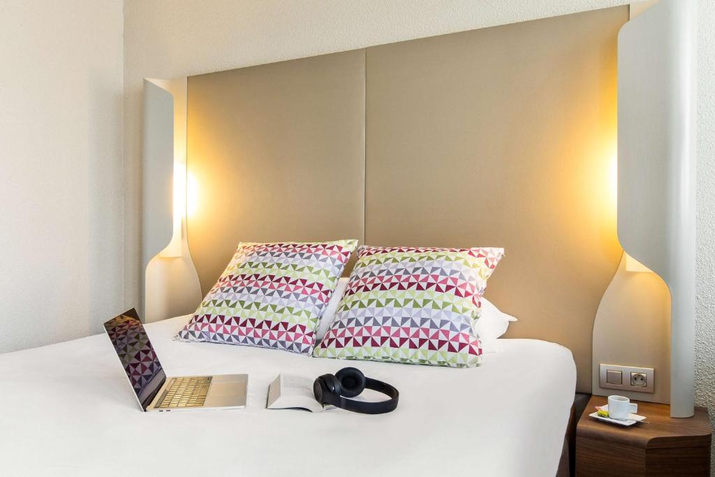 a bed with two pillows and a book on it at Campanile Annecy - Cran Gevrier in Annecy