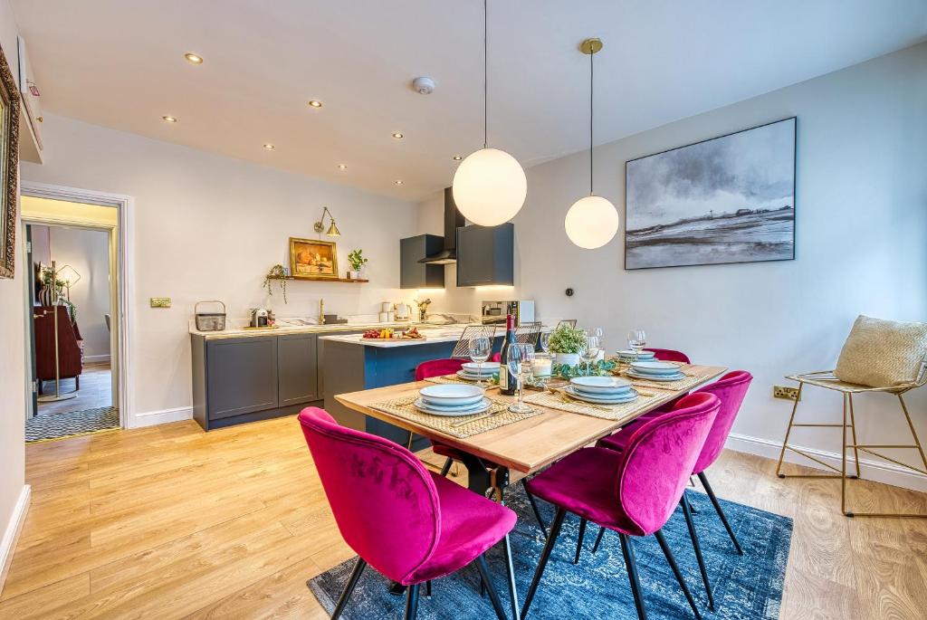 a kitchen and dining room with a table and pink chairs at Haworth Heights - An AMAZING Aparthotel! in Haworth