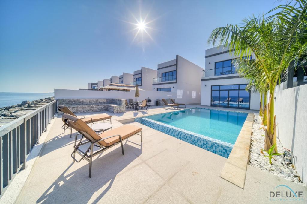 a villa with a swimming pool next to the ocean at Dazzling 4BR Villa with Assistant’s Room at Al Dana Villa Sharm, Fujairah by Deluxe Holiday Homes in Fujairah