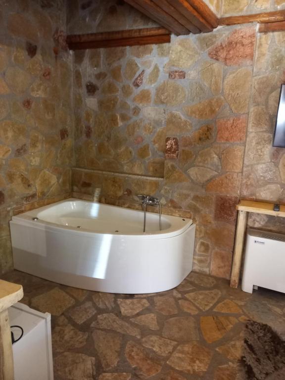 e bagno con vasca e parete in pietra. di Ζachlorou Mood a Kalavrita