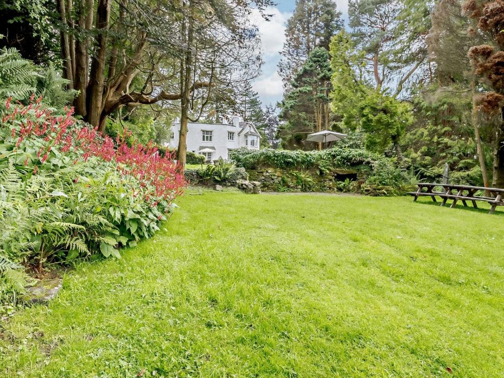 un parc avec un banc, des fleurs et une maison dans l'établissement 1 Bed in Machynlleth 93081, à Cemmaes