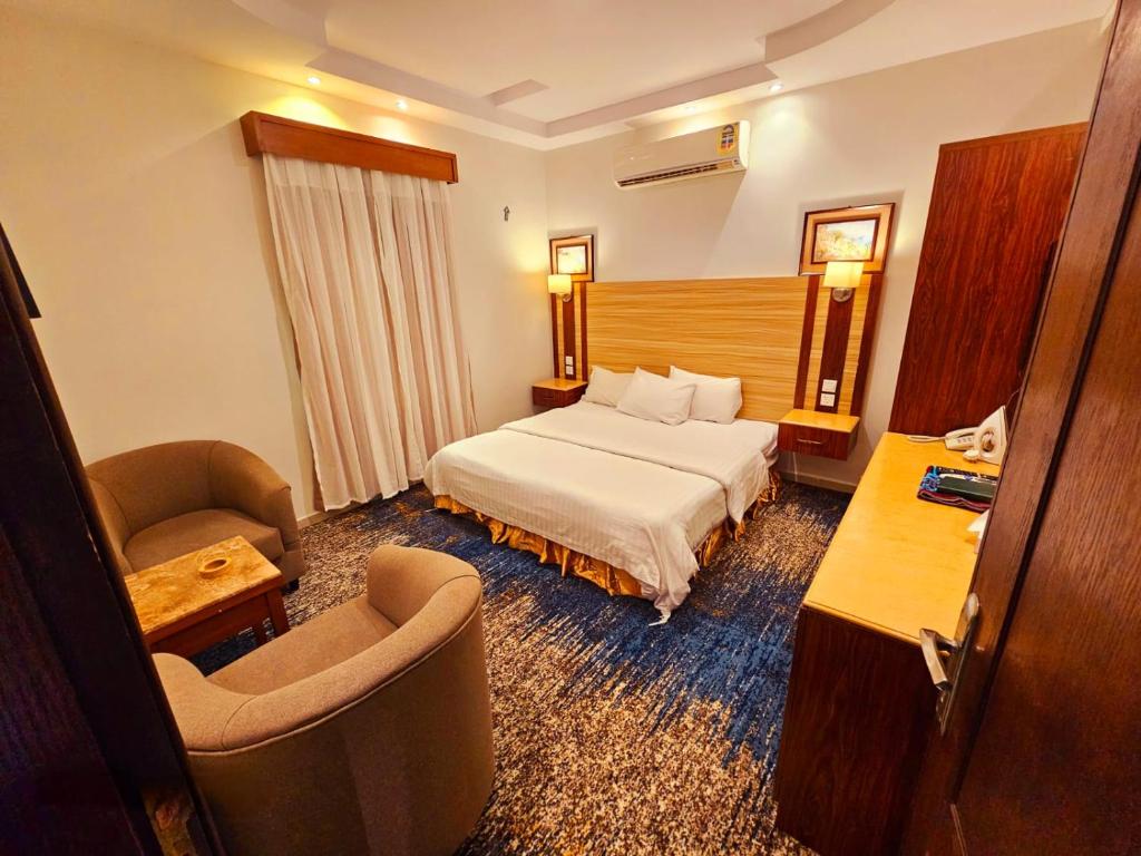 a hotel room with a bed and a chair at قصر البسمة للشقق المخدومةSMILE Serviced Apartments in Jeddah
