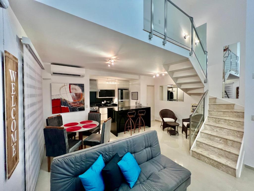 a living room with a couch and a staircase at Duplex Morumbi Luxo in São Paulo