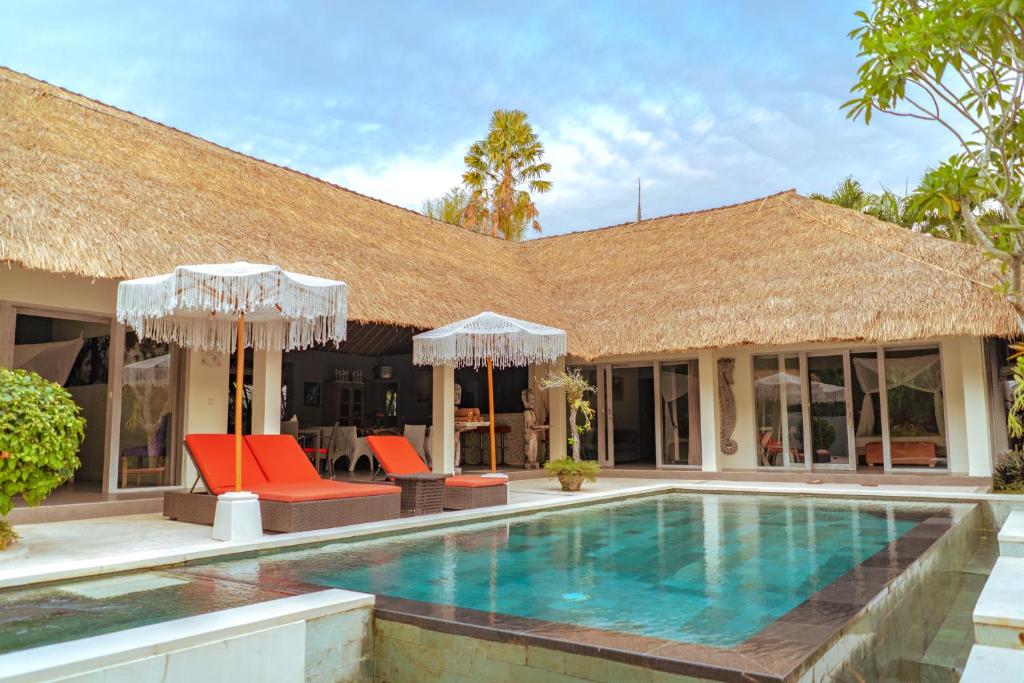 a villa with a swimming pool and orange chairs at Maylie Bali Villa & Bungalows in Canggu
