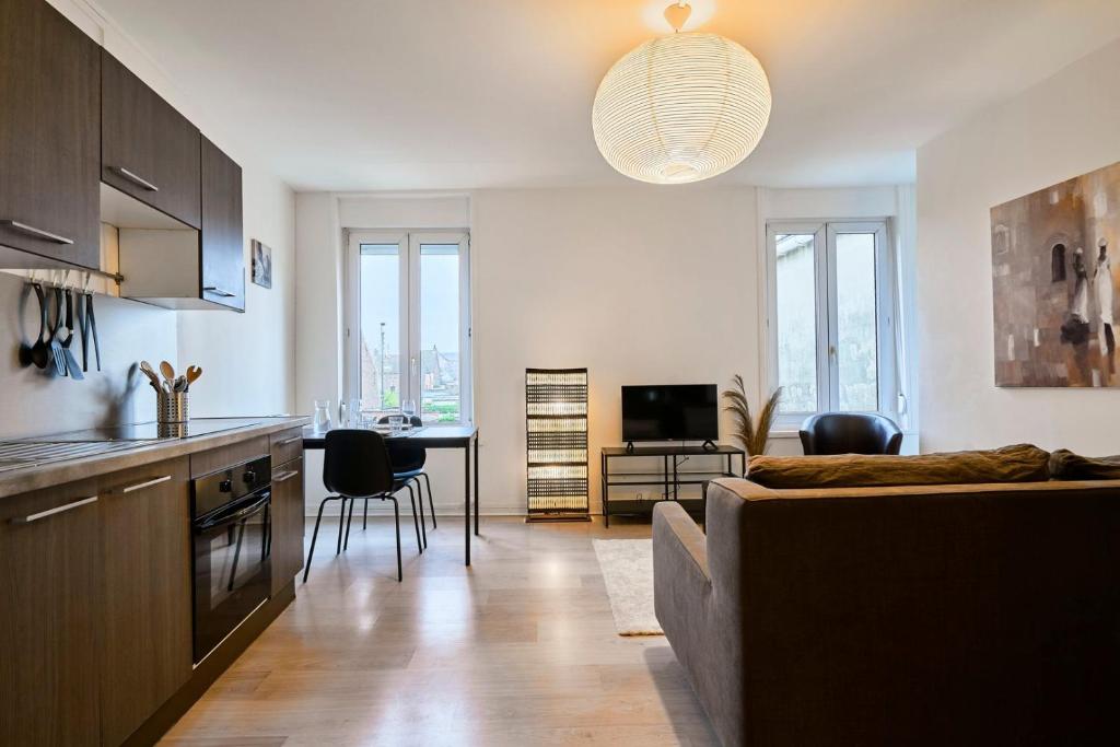 cocina y sala de estar con sofá y mesa en One bedroom apartment near tramway & shops en Mouvaux