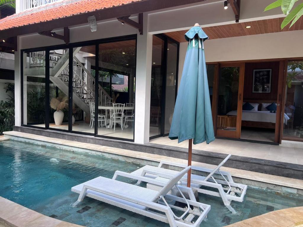 - deux chaises et un parasol dans la piscine dans l'établissement Villa Baru 3 Bedroom, à Tabanan