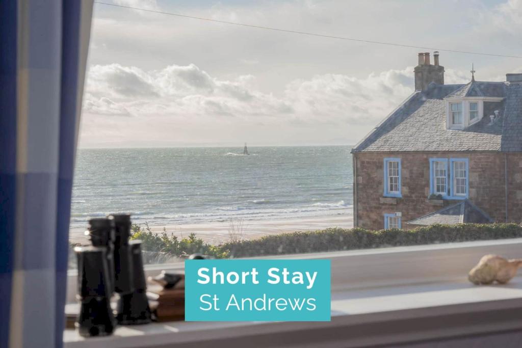 a window with a view of the ocean and a house at Stonesthrow Elie, 2 Mins to Beach, Free Parking in Elie