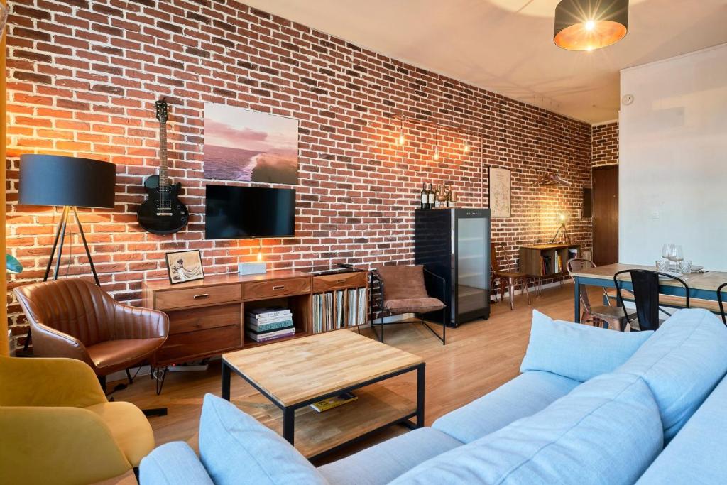 un salon avec un canapé et un mur de briques dans l'établissement 1 bedroom apartment near metro, shops & schools, à Lille
