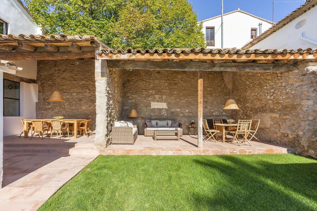 un patio al aire libre con una pared de piedra y césped verde en Finca Can Romeu alojamiento rural entre viñedos en Font-Rubí