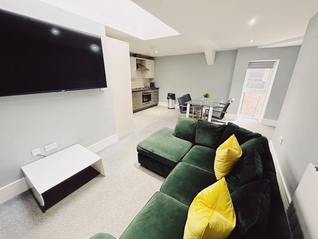un soggiorno con divano verde e TV a schermo piatto di 2 Bedroom Apartment in the Heart of Newcastle - Modern - Sleeps 4 a Newcastle upon Tyne