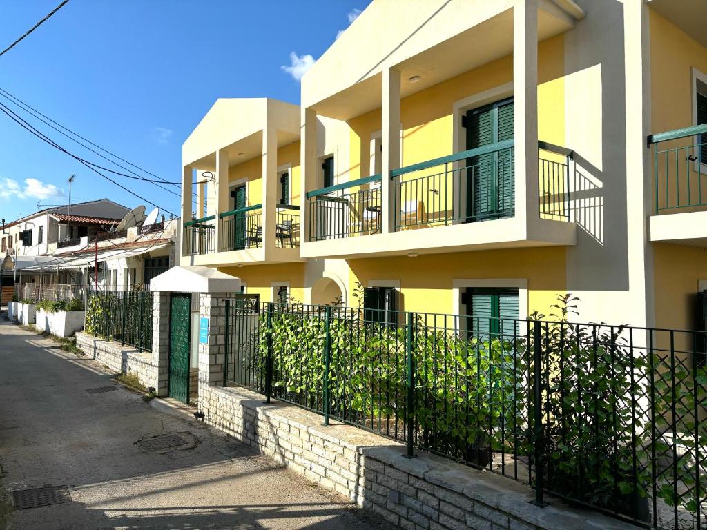 a yellow and white building with a fence at Nelly's Luxury Suites in Kassiopi