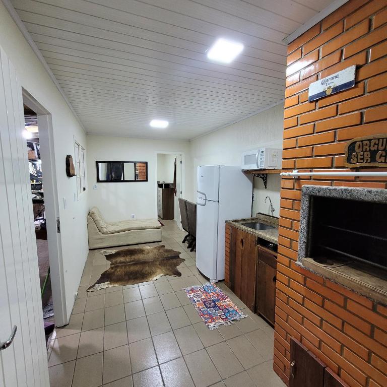 eine Küche mit einem Kühlschrank und einer Ziegelwand in der Unterkunft Kitnet em Torres 2 pessoas in Torres