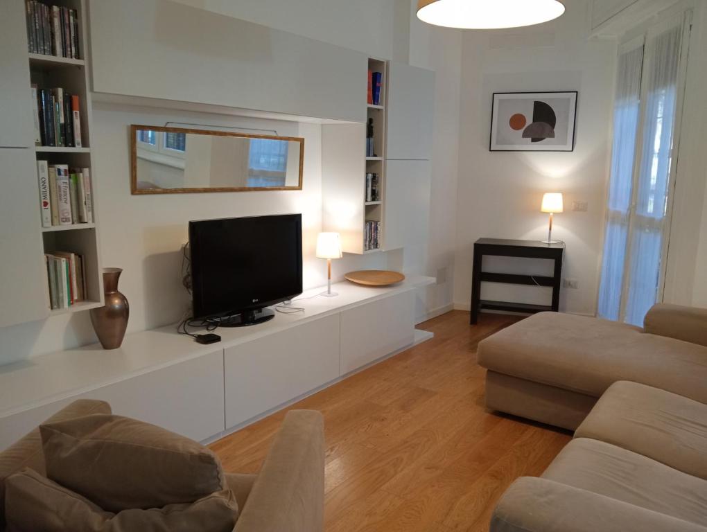 uma sala de estar com uma televisão de ecrã plano e um sofá em SANDONHOUSE MILANO em San Donato Milanese