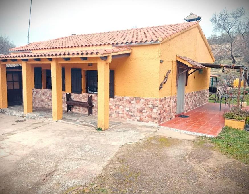 una casa amarilla con un banco delante en Casa rural Los Barreros en Ciudad-Rodrigo