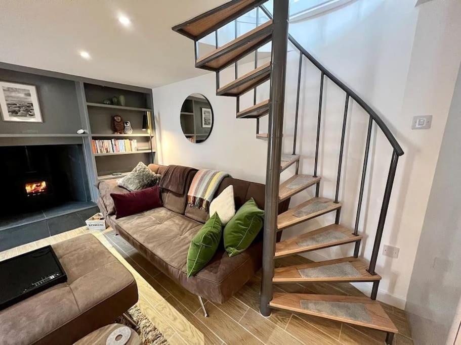 a living room with a couch and a spiral staircase at Studio House in St Margaret's Hope