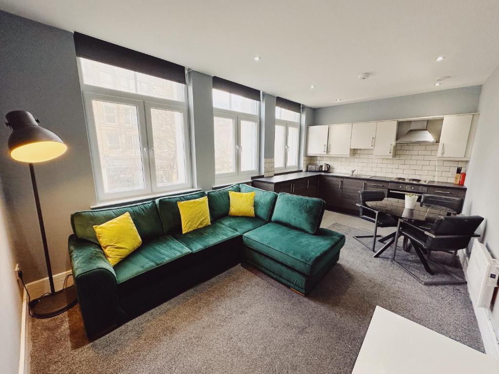 a living room with a green couch and a kitchen at 3 Bedroom Apartment in the Heart of Newcastle - Modern - Sleeps 6 in Newcastle upon Tyne