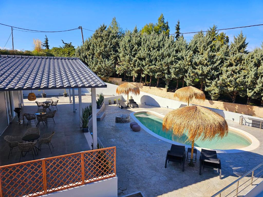 a pool with straw umbrellas and tables and chairs at Dream Luxury Suites & Apartment in Pastida
