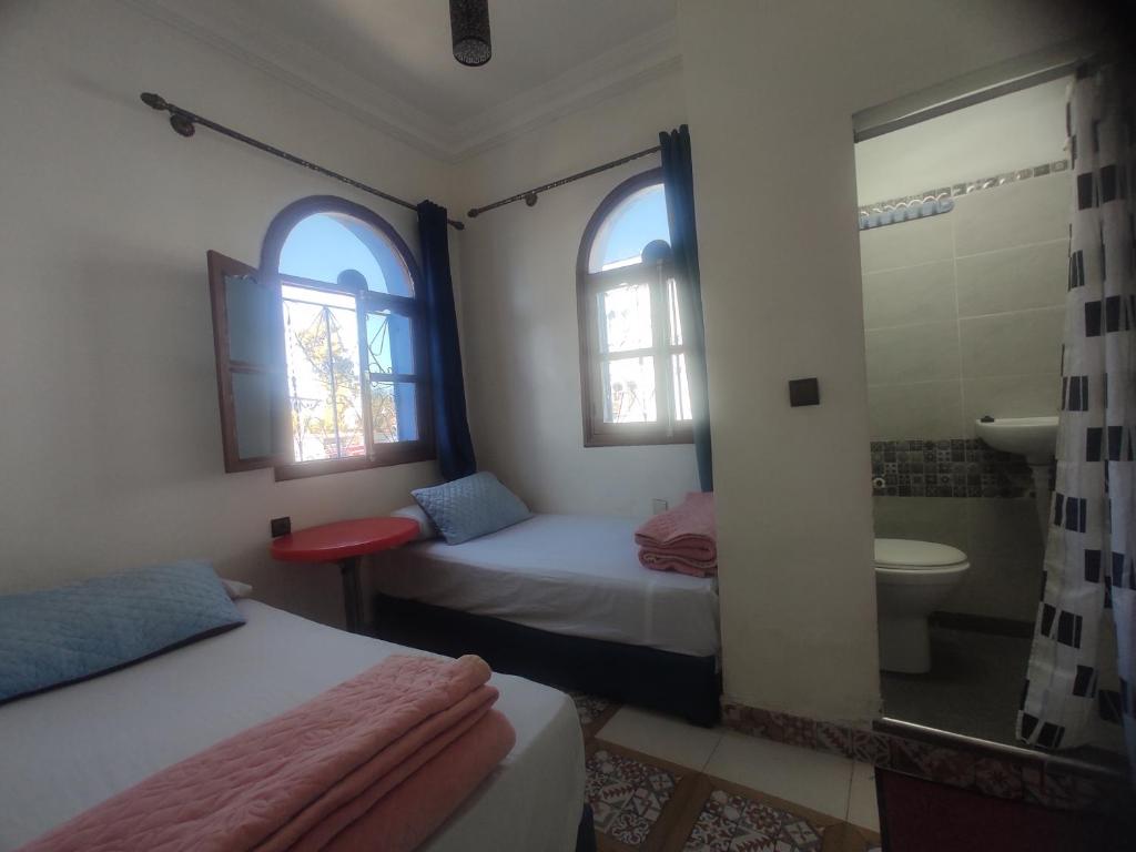 a bedroom with two beds and a bathroom with a shower at casa embassadeur in chefchaouen in Chefchaouen