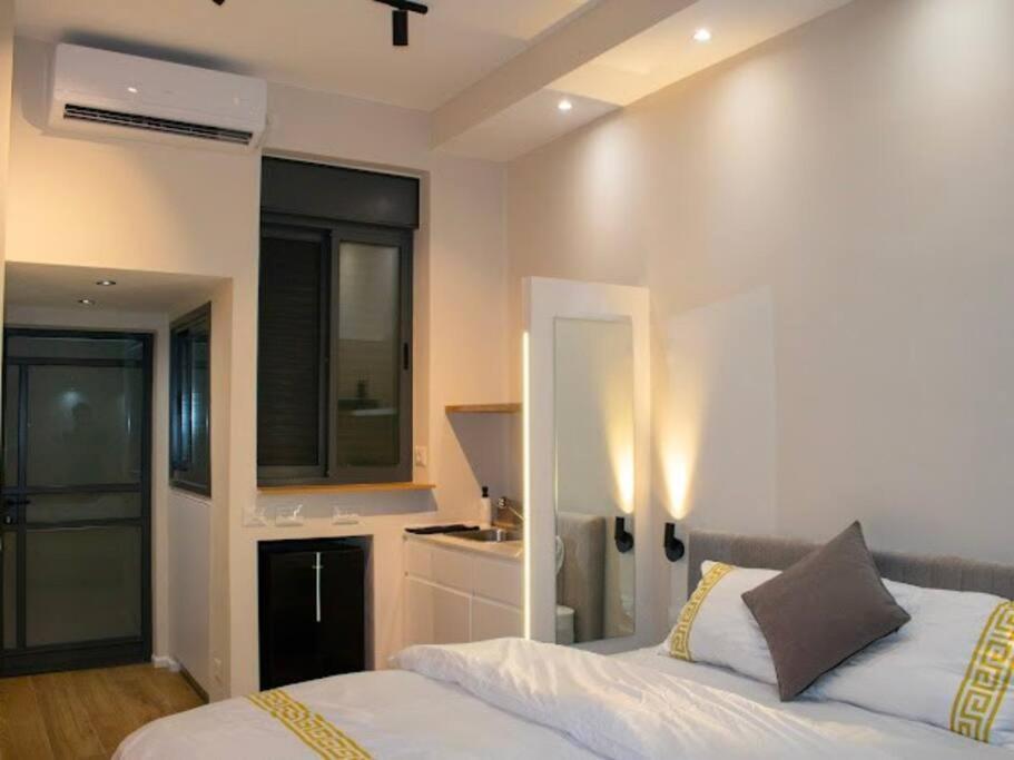 Cet appartement comprend une chambre avec un grand lit blanc et une cuisine. dans l'établissement דירת גן יפהפיה בחובבי ציון, à Tel Aviv