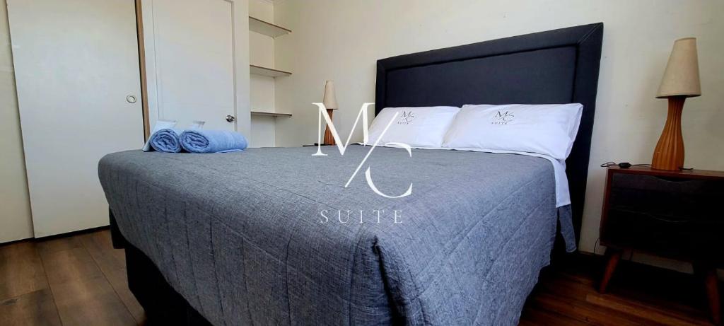 ein Schlafzimmer mit einem Bett mit einer blauen Decke und weißen Kissen in der Unterkunft MC Suite - Centro in Antofagasta