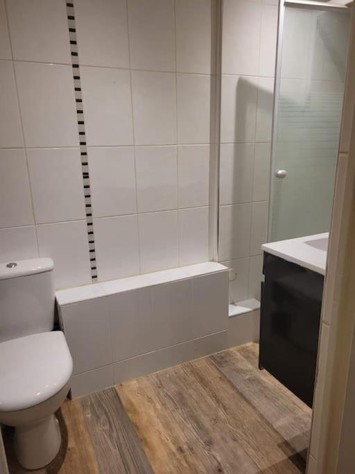 La salle de bains blanche est pourvue d&#39;une douche et de toilettes. dans l&#39;établissement Appartement 2 chambres 1 salle de bain Paris 8eme Champs Elysées, à Paris