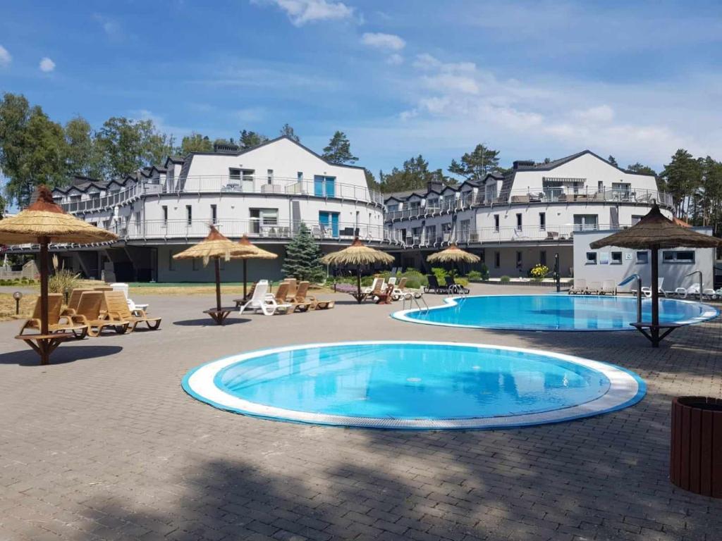 a resort with two pools and umbrellas and buildings at Romantyczny Apartament HAPPY 16 BASEN & KORT TENISOWY, OCHRONA 24 h - dla maksymalnie 6 osób in Pobierowo