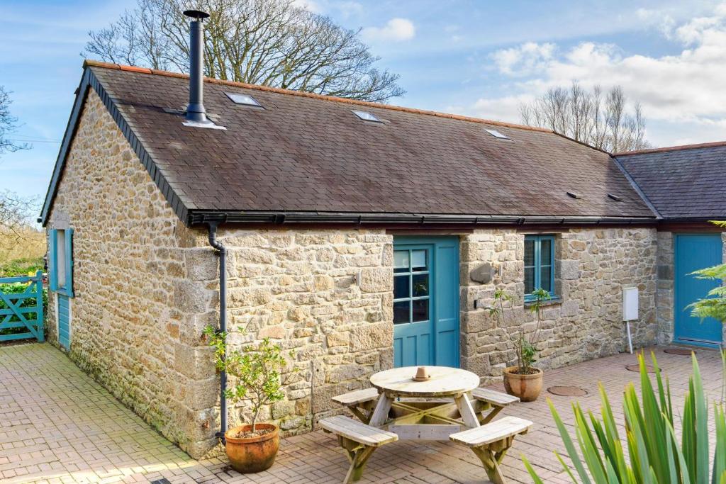 a stone cottage with a table and a blue door at Lamorna in Mawnan Smith