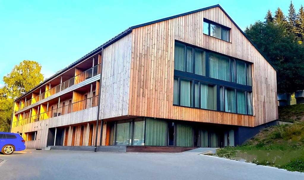 un edificio de madera con un coche aparcado delante de él en Residence Alpina en Špindlerův Mlýn