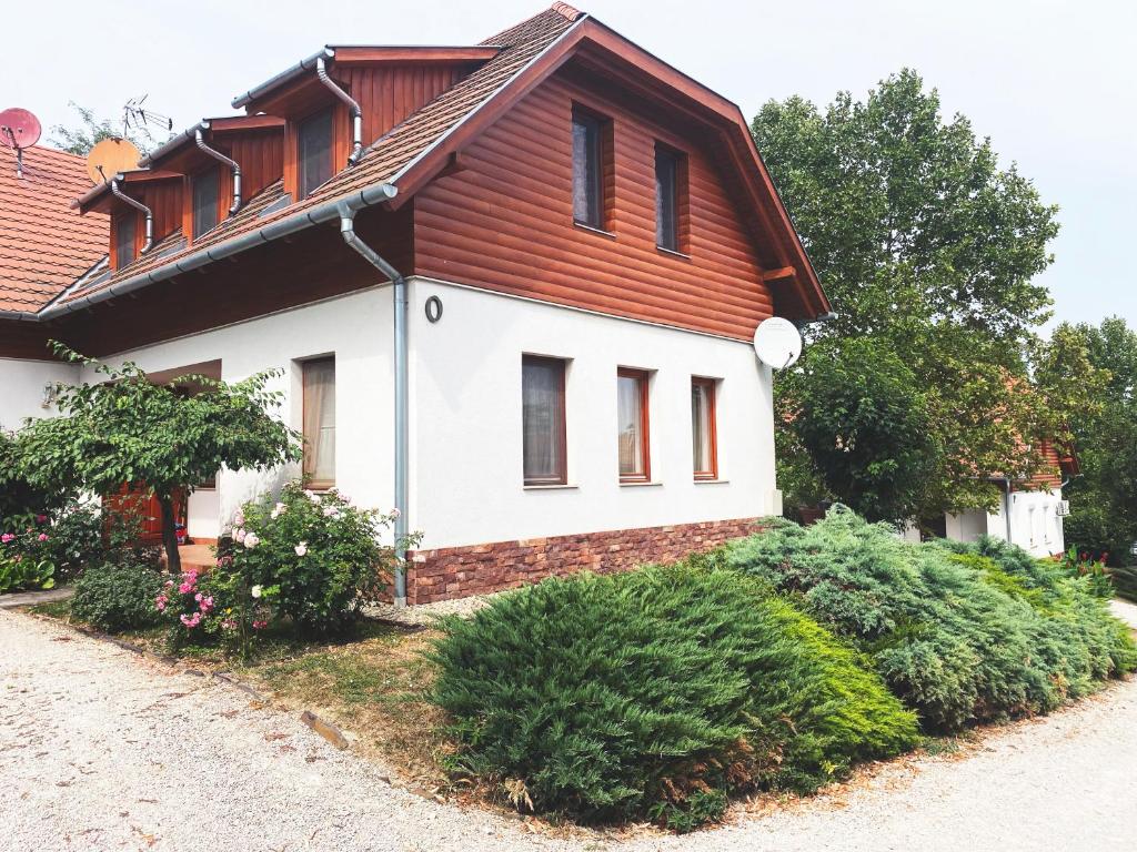 Biały dom z czerwonym dachem i krzakami w obiekcie Thermal Valley Apartman - Batthyány Villapark w mieście Zalacsány