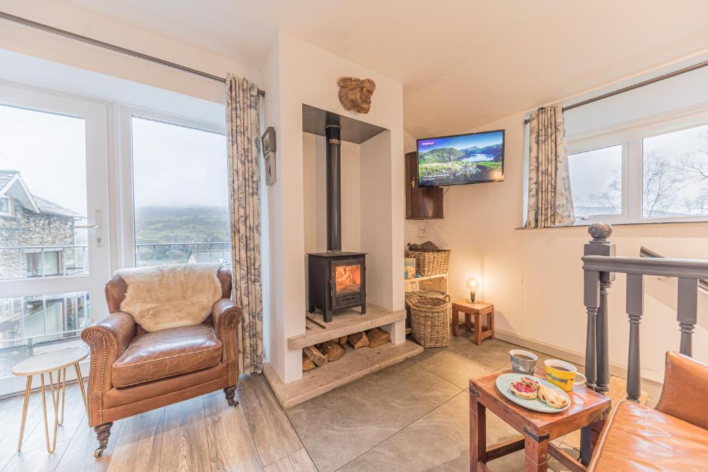 a living room with a fireplace and a chair and a television at Romantic getaway, little two bed, two bath barn conversion with amazing views and parking in Ambleside